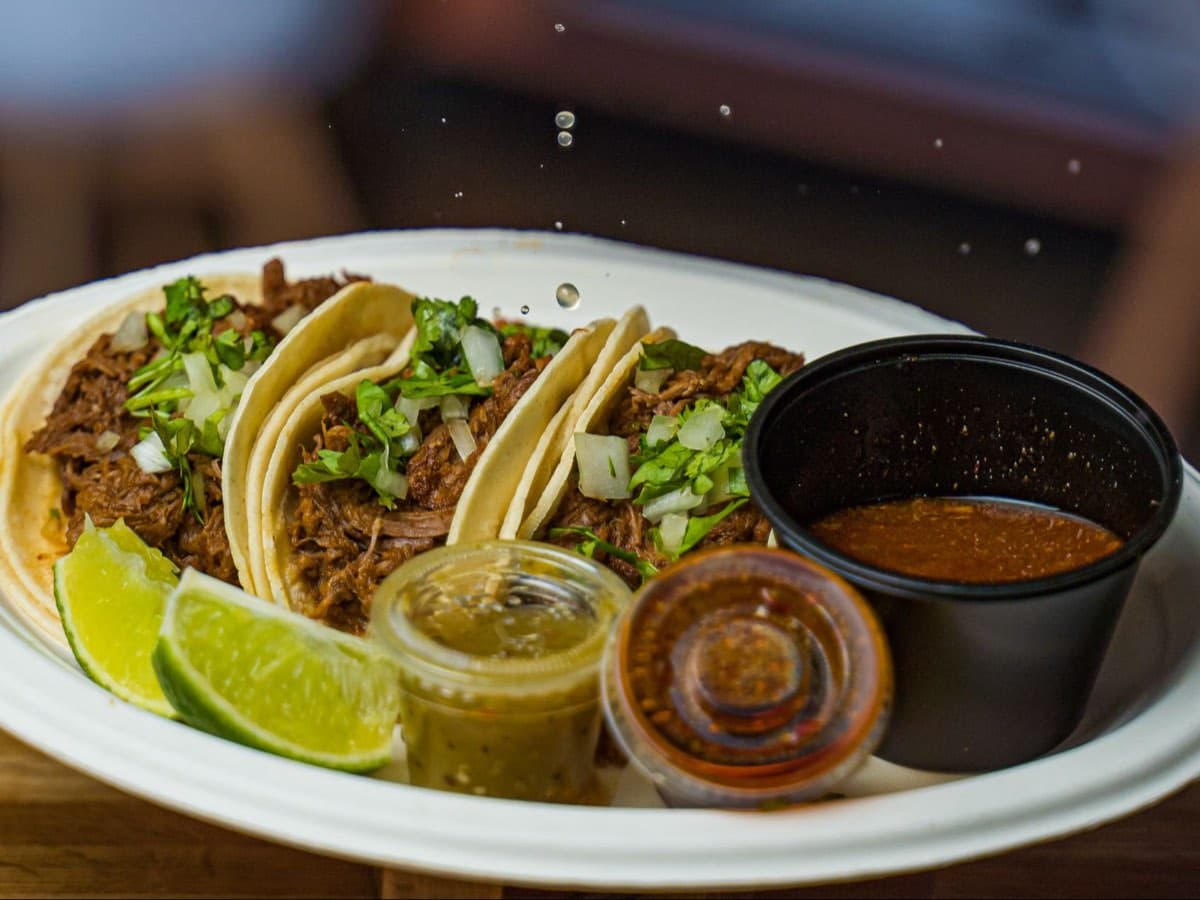 Testal birria tacos with consomé, lime, and salsa